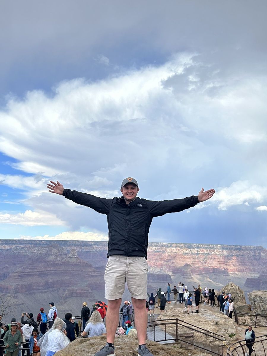 Alex with his arms spread wide at the rim of the Grand Canyon